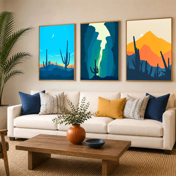 A set of three framed desert landscape art prints. The prints showcase stylized cacti and mountains in vibrant shades of blue, teal, orange, and yellow.
